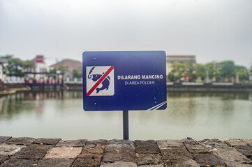 A No Fishing sign at a polder area, prohibiting fishing activities in a serene urban water body....