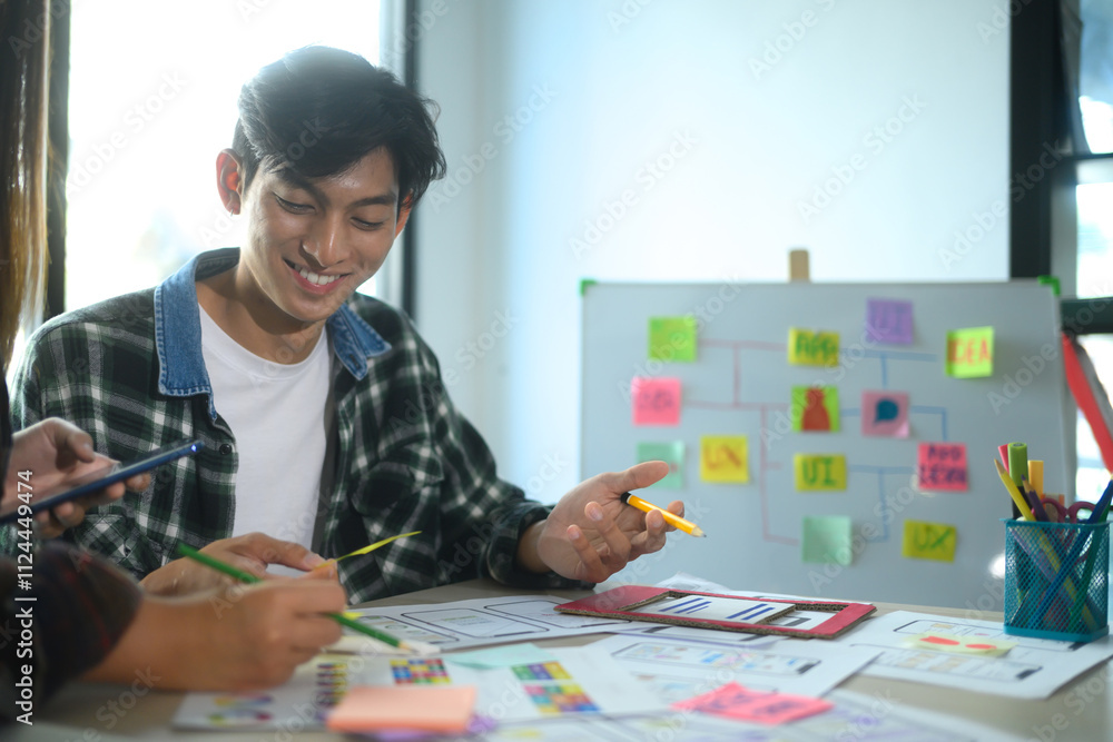 Poster cheerful young man collaborating with his team on app design and ui ux development in the office