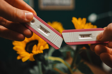 Positive pregnancy test held by future parents with yellow sunflower background. Two pregnancy...
