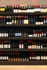 Front view of wine bottles on shelves in wine shop.