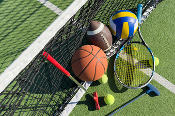 football soccer ball basketball tennis ball and racket laid on grass at sunset