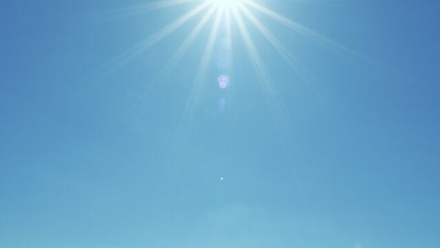 Bright Shining Sun In A Blue Sky No Clouds. Sunbeams And Flares Shining On Sunny Clear Blue Sky Background In Tropical Summer. Sunny Day.