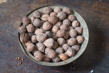 Walnuts in a copper bowl on the wooden surface