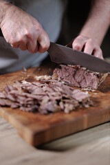 Male hands cutting cooked meat beef on a wooden board