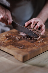 Male hands cutting cooked meat beef on a wooden board