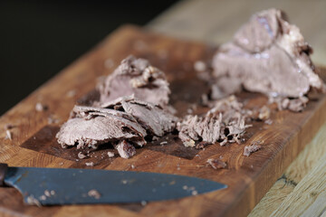 Male hands cutting cooked meat beef on a wooden board