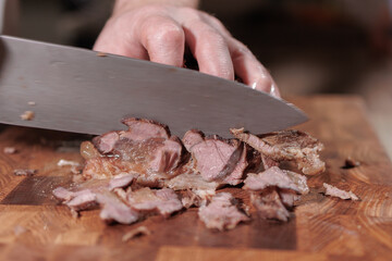 Male hands cutting cooked meat beef on a wooden board