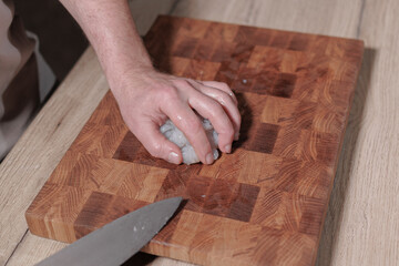 Male hands cutting raw shrimp on wooden board
