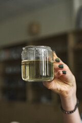 A Hand Holding a Glass Jar of Herbal Tea While Sitting in a Cozy Atmosphere Filled with Warmth