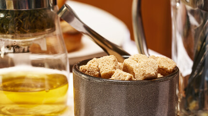 A cup with brown cane sugar in close-up. Table setting.      