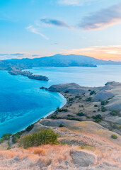 View of the sea surrounded by hills with grass hill with the turquoise color of the sea and yellowish shades of the sunset at Gili Lawa, Labuan Bajo, East Nusa Tenggara, Indonesia © Balnyes Visuals