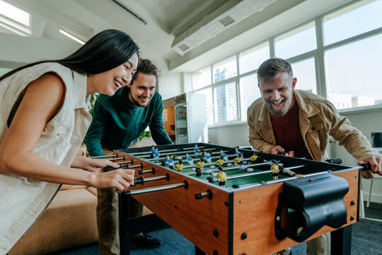Cheerful business people playing foosball in office