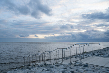 Handrail at the coast of Norddeich, East Frisia, Germany during high water with a dramatic sky.