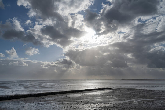 Dramatic sky over the North Sea during ebb tide in Norddeich, Lower Saxony, Germany.
