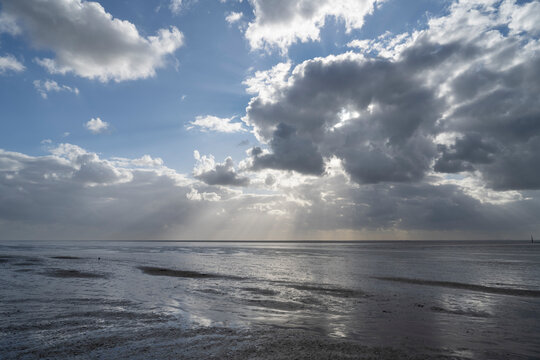 Dramatic sky over the North Sea during ebb tide in Norddeich, East Frisia, Germany.