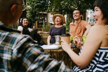Group of friends enjoying a casual gathering outdoors with coffee and smiles.