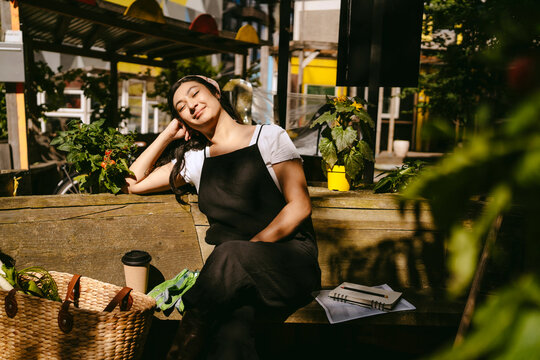 Young woman relaxing in an urban garden on a sunny day.