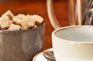 Coffee cup and cup with brown sugar on a wooden table. Soft focus.     