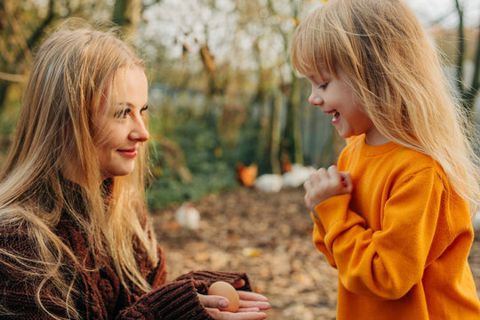 Happy mother showing egg to daughter in village