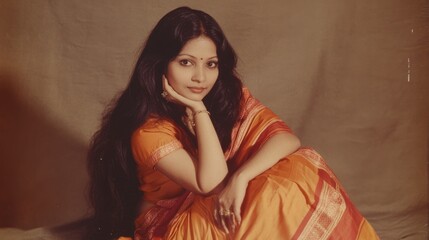 Elegant woman in traditional orange attire with long hair in a seated pose