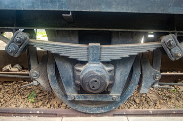 Close up of a vintage train wheel and suspension system, showcasing the intricate engineering and robust construction of historical railway technology