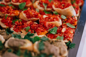 Eine Platte mit frischen Bruschetta, belegt mit fein gewürfelten Tomaten, Kräutern und Basilikum,...