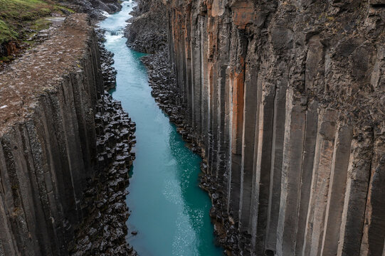 Aerial view of the famous Studlagil Canyon with columnar basalt rock formations and blue-green water of the river J�kla in Iceland.