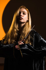 A red-haired woman magician casts a spell with a magic wand against the backdrop of a crescent...
