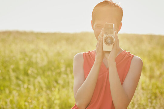 Woman filming with 8mm camera in field