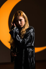 A red-haired woman magician casts a spell with a magic wand against the backdrop of a crescent moon. Portrait of a young sorceress. The concept of magic and sorcery