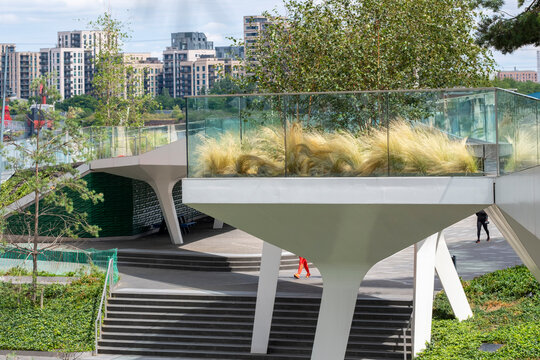 A stylish walkway overlooking lush greenery and urban architecture, promoting a harmonious blend of nature and city living, offering an inviting path for exploration and relaxation in London UK
