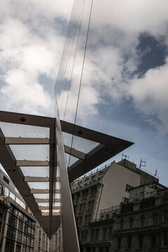 The striking lines and reflective surfaces of urban architecture blend with the sky and clouds, showcasing modern design principles that emphasize clarity, innovation, and beauty within cityscapes in