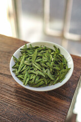 Fresh green tea leaves displayed in an elegant bowl, showcasing their beauty and aroma