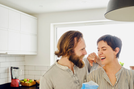 Playful couple spending leisure time preparing food in kitchen at home