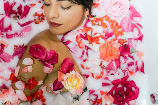 Woman relaxing in a floral milk bath indoors