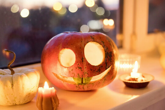 Carved pumpkin for Halloween on a windowsill in Ukraine with candles and festive atmosphere