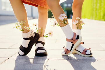 Fresh flowers in socks of girls standing on footpath