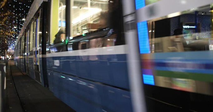 03-12-2024 Zurich, Switzerland. Trams 13 and 7 riding on famous shopping street Bahnhofstrasse at night in December. Illuminated streets, Christmas decoration lights, real time footage