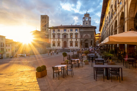 Sidewalk cafe in Piazza Grande with church of Santa Maria Della Pieve at sunset, Arezzo, Tuscany, Italy
