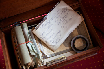 A handwritten old letter in an opened old wooden box containing various documents and analogue photographs.