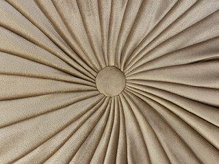 Close up of bead fabric puff seating with sunburst pattern in beige gold color. Suede sunburst...