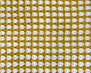 Close up of yellow knitting fabric. Yellow and white scarf fabric seamless background texture. Knitting concept, suitable for clothing. Seamless background fabric texture.