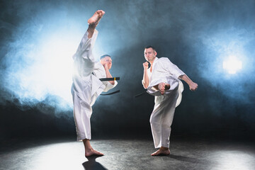 Martial arts masters on dark background. Strong man fighters in white kimono for karate martial...