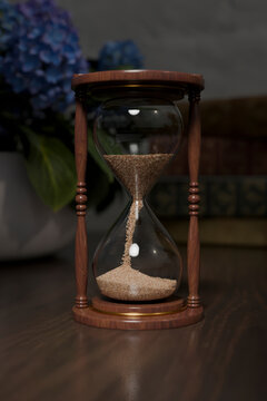 Wooden sandclock with blue flowers in the background.