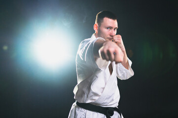Strong man fighter in white kimono for karate martial arts with black belt preparing for fight...