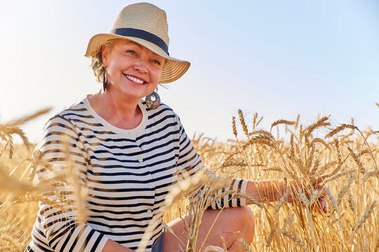 Smiling mature woman amidst wheat crops in farm
