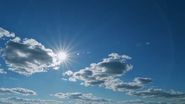 Rays of the sun make their way through the clouds at blue sky. Sunlight with sunbeams. Timelapse.
