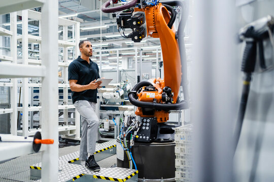 Technician examining industrial robot in a factory