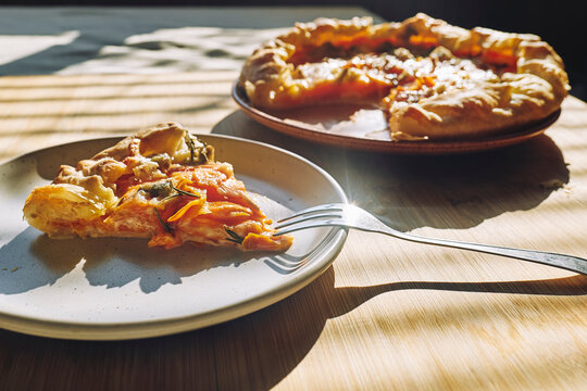 Delicious seasonal tart with baked pumpkin, brie cheese and herbs on wooden table