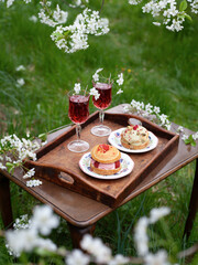 Spring picnic in blooming apple orchard -  vintage table cherry cocktails and sweet cakes are perfect setting for a romantic date.